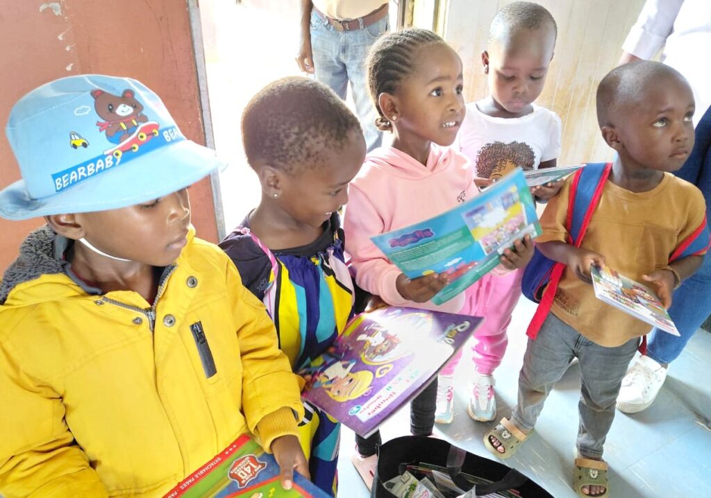 Children enthusiastically explore colorful books, showcasing their engagement in a reading activity within a bright, inviting space.