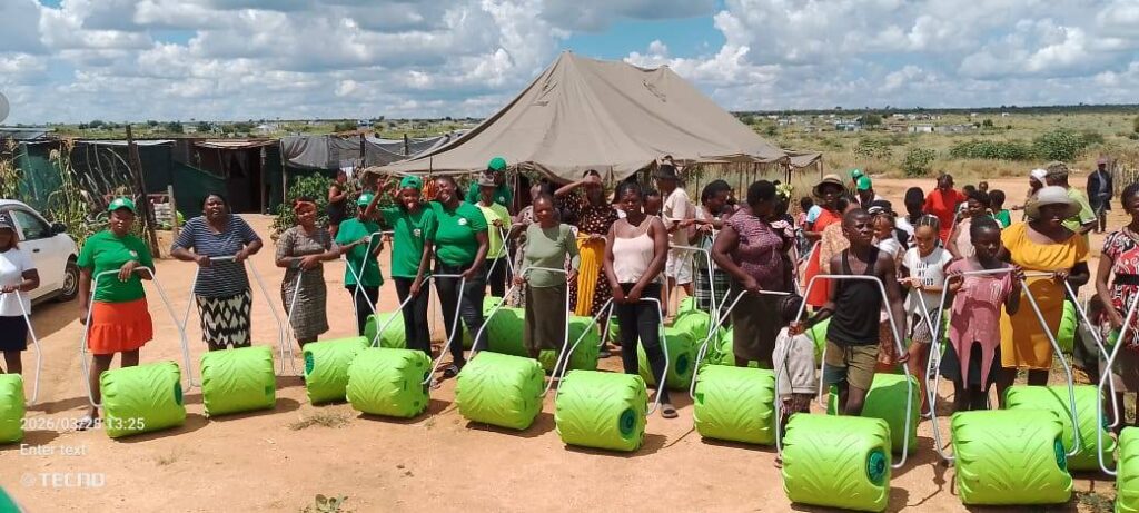 Women in green shirts proudly display new farming equipment in a rural community, promoting agricultural development and empowerment.